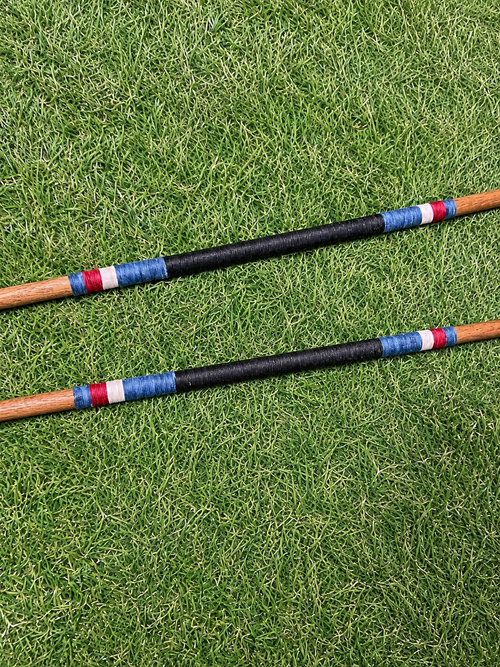 Two custom hand-wrapped hickory golf alignment sticks on grass
